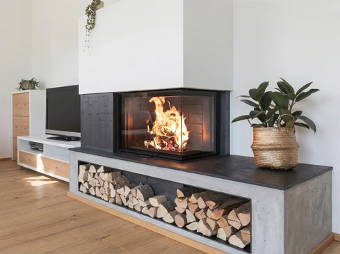 Intérieur moderne avec cheminée encastrée allumée dans mur de briques blanches peintes, sol en parquet bois naturel
