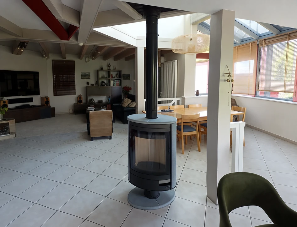 Intérieur domestique chaleureux avec poêle à bois en fonte noire en fonctionnement, flammes visibles par la vitre